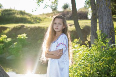 Suda beyaz elbiseli, çelenkli küçük bir kız. Tatil İvana banyo yaptı.