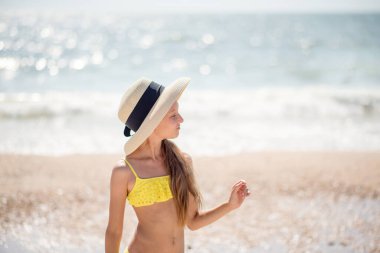 Bikinili genç bir kadın. Şapkalı kız. Okyanus kenarındaki sarı mayolu uzun saçlı güzel kız. Seyahat ve rahatlama. Aile bağlantısı. spor ve eğlence.