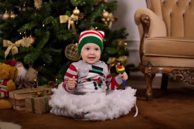 Noel ağacı olan küçük bir kız. Noel Baba şapkalı küçük kız. Oyuncak taşıyan küçük kız.