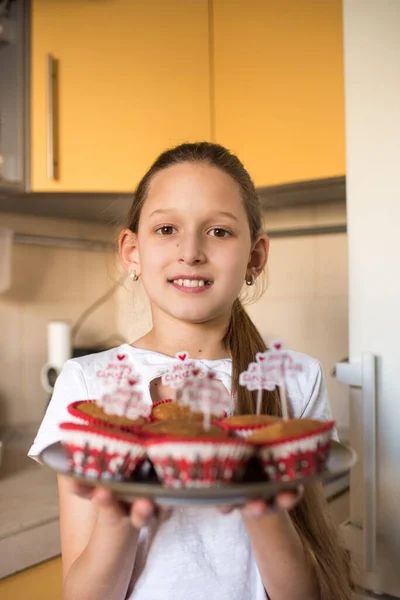 女の子保持トレイともに陽気なクリスマスカップケーキでキッチン — ストック写真