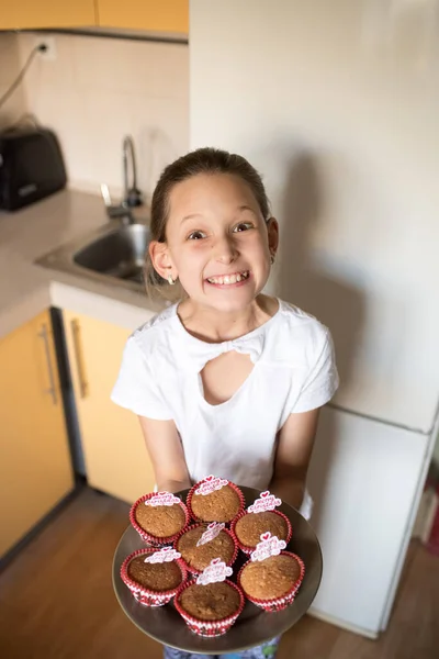 女の子はケーキを食べる 台所で料理する若い女性 チョコチップマフィンよ アイシングとクリスマスカップケーキ — ストック写真