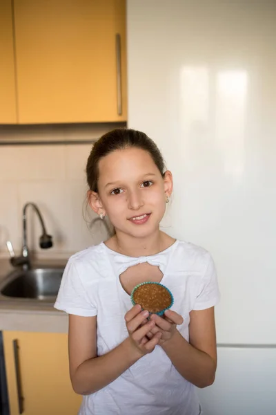 女の子はケーキを食べる 台所で料理する若い女性 チョコチップマフィンよ アイシングとクリスマスカップケーキ — ストック写真
