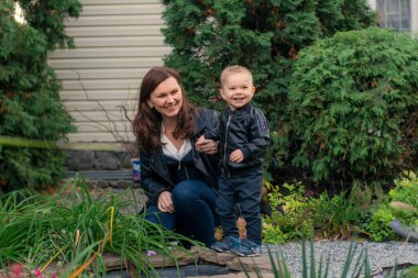 Anne ve çocuk parkta. Aile sonbahar parkında yürüyor. Anne ve oğul gülümsüyor ve mutlu.