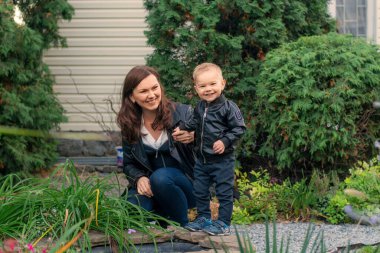 Anne ve çocuk parkta. Aile sonbahar parkında yürüyor. Anne ve oğul gülümsüyor ve mutlu.