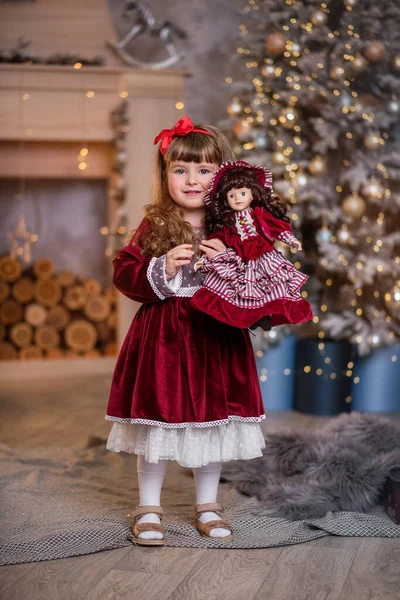 크리스마스 근처빨간 드레스를 인형을 크리스마스 놀이를 아이는 미소를 짓습니다 머리가 — 스톡 사진
