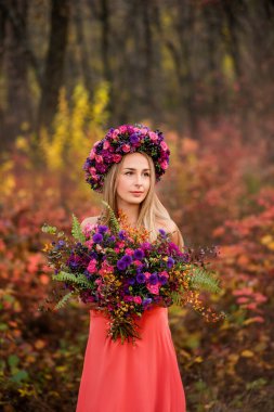 Çelenk takmış güzel bir genç kadın ve sonbahar parkında bir buket çiçek. Güzel çiçekçi kız..