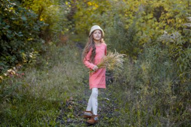 Sonbahar parkında uzun saçlı güzel kız yürüyor. Yürüyüşe çıkmış mutlu çocuk.
