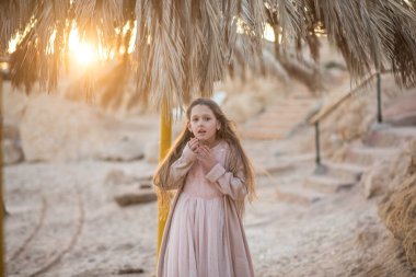 Kumsaldaki güzel, uzun saçlı kız. Kız başını tutuyordu. Baş ağrısı. Kız hapşırır