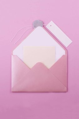 Pink open envelope-letter with a wax seal and a paper label for signing on a light purple background. It is embedded with a yellow note sticker on which you can write any message, for example romantic. clipart
