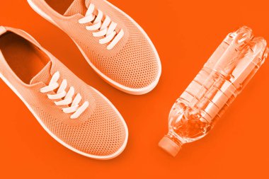 Parlak turuncu zemin - ışık turuncu spor ayakkabı, bir şişe su turuncu bir arka plan üzerinde düzen.