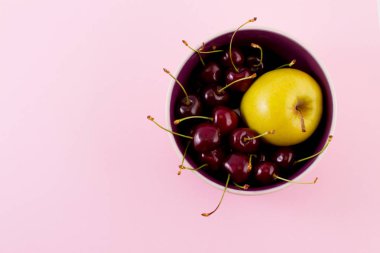 Parlak olgun tatlı bakir ve pastel pembe bir arka plan üzerinde bir tabak içinde sarı sulu elma.