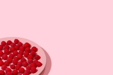 Arka plan parlak olgun sulu ahududu pastel ateşin üzerinde pastel pembe tabakta pembe.