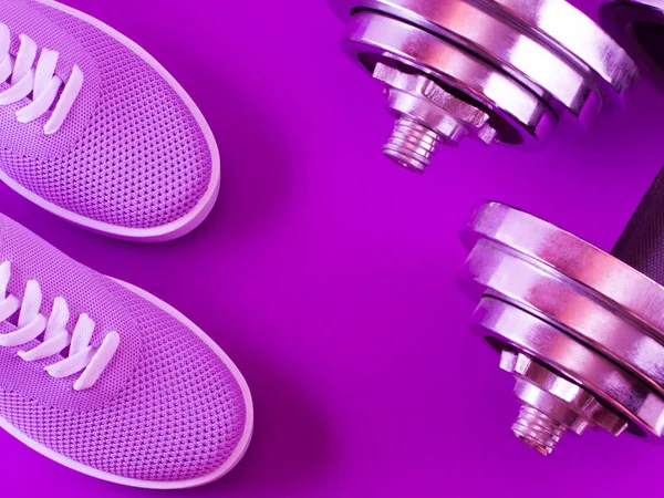 Bright violet sneakers on a purple background with dumbbells from several parts.