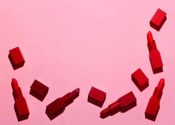 一组鲜红的口红被铺在柔和的粉红色背景上 有一个刻题词的地方 — 图库照片