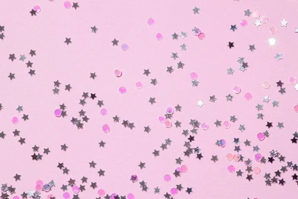 Pink sequins on a pink pastel background with confetti as asterisks.