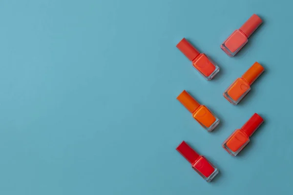 Naranja esmalte de uñas botella sobre un fondo de papel turquesa — Foto de Stock