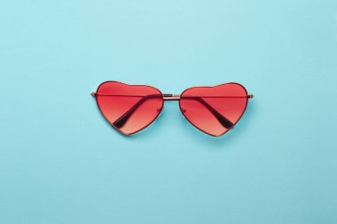 Bu sezon moda turuncu renk teması Trend fotoğraf. Turkuaz Kağıt arka planda parlak turuncu kalp şeklinde gözlük.
