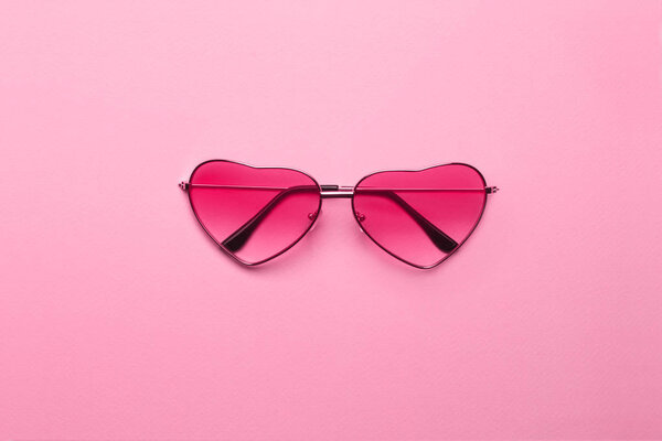 Ярко-розовые очки в форме сердца на фоне розовой бумаги
.