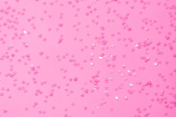 粉红色背景上的粉红色亮片，纸屑为星号. — 图库照片