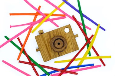 Beyaz arka planda ahşap kamera, renkli çizgili toplarla çevrili..