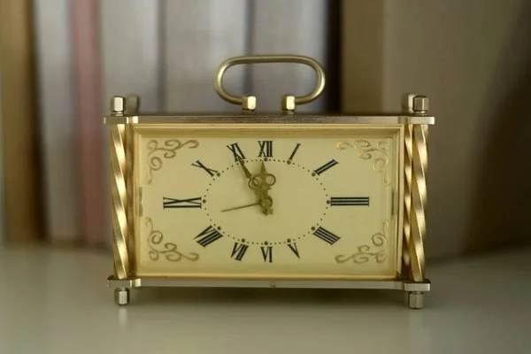 old gold clock shows five minutes to twelve o\'clock