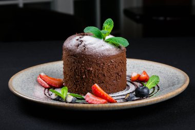 çilek ve karanlık bir arka plan üzerinde yaban mersini ile çikolatalı kek