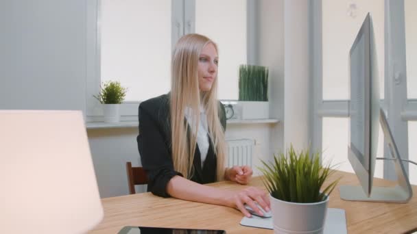 Vrouw met duimen naar beneden in het kantoor. Zitten op de werkplek jonge blonde vrouw in business suit kijken naar de camera en doen duimen neer gebaar van afkeuring of afkeer. — Stockvideo