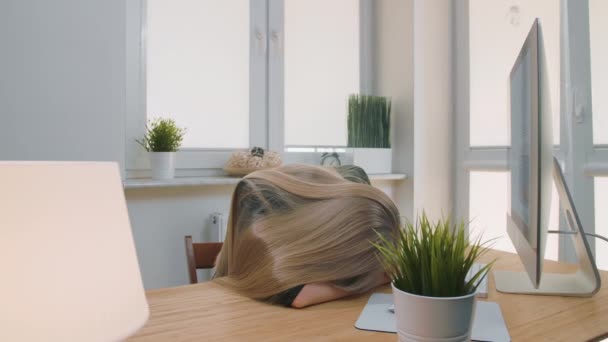Mujer cansada despertando en el lugar de trabajo. Trabajadora de oficina rubia cansada en traje elegante relajada tumbada en los brazos en el escritorio luego levantarse bostezando y comenzar a trabajar en la computadora en la sala de luz con plantas . — Vídeos de Stock