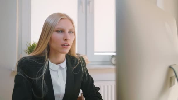 Verontrustende vrouw op het werk. Blond triest vrouwtje in elegante kleren knijpen hoofd na mislukking of slecht nieuws zittend in licht kantoor aan het bureau met computer. — Stockvideo