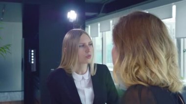 Ofiste konuşan kadın coworking. Konuşmayı modern ışık ofiste arkasında yanan lamba ile takım elbiseli iki yetişkin resmi kadın.