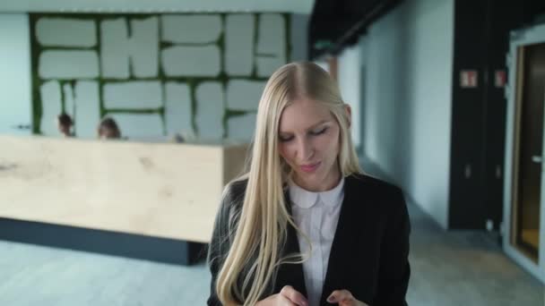 Vrolijke vrouw in kantoor zwaaien met de hand. Elegante jonge dame in jas zwaaien met hand aan anonieme persoon groeten terwijl u werkt in office. — Stockvideo