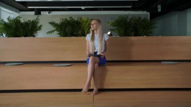 Ofiste tablet ile rahatlatıcı bir kadın. Çıplak ayakla tablet ve alarak dinlenme kullanarak modern ofis ahşap kürsü üzerinde oturan genç zarif kadın.