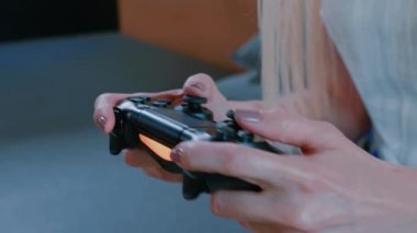 Rahatlatıcı kadın kapalı konsolu oynuyor. Kanepede ürpertici ve modern iç gamepad ile video oyunu oynayan genç casual kadın.