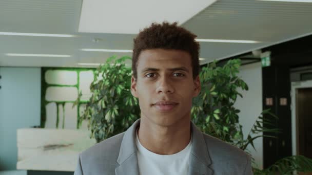 Schöner schwarzer Mann im Anzug. Junger afroamerikanischer Mann im eleganten Anzug steht im modernen Büro und lächelt glücklich in die Kamera. — Stockvideo