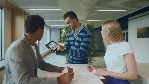 Multiethnische Mitarbeiter mit Papieren und Tablet. Seitenansicht eines schwarzen Mannes mit Mitarbeitern am Tisch, die Zeitungen lesen und Tablet im Team am Tisch benutzen. — Stockvideo