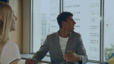 Ofisteki meslektaşlarıyla gülen siyah adam.