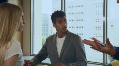 Çalışma sürecinde olan bir grup insan. Çok ırklı erkek ve kadın iş konularını tartışırken ofisin aydınlık odasında yan yana duruyorlar..