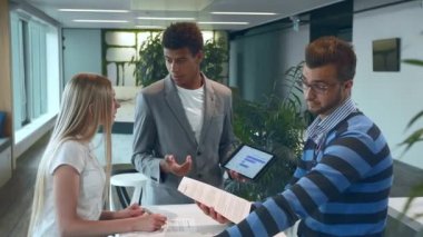 Rapor üzerinde çalışan çok ırklı erkek ve kadın. Modern ofis salonunda çeşitli kadın ve erkek grupları belgeler ve istatistikler üzerinde çalışıyorlar..