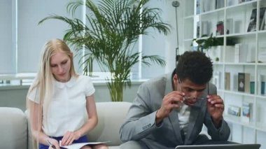 Siyahi adam iş arkadaşlarıyla iyi haberleri paylaşıyor. Afro-Amerikalı adam dizüstü bilgisayarda sörf yapıyor ve harika haberleri iş arkadaşlarıyla paylaşıyor. Masanın etrafında birlikte oturuyorlar..