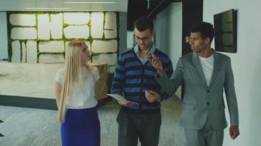 Ofis salonunda çeşitli iş arkadaşları. Office salonda yer gösterme ve eğlence içinde konuşan arkadaşları ile yürüme takım elbiseli adam.