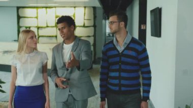 Ofis salonunda çeşitli iş arkadaşları. Office salonda yer gösterme ve eğlence içinde konuşan arkadaşları ile yürüme takım elbiseyle siyah adam.