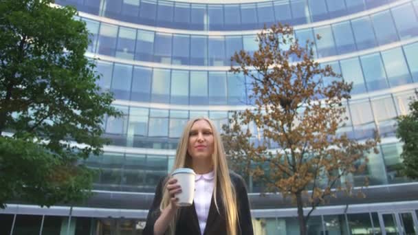 Femme d'affaires élégante avec café dans la rue. D'en bas de femme exécutive blonde grave en costume prenant un café dans une tasse en papier regardant loin dans la rue . — Video