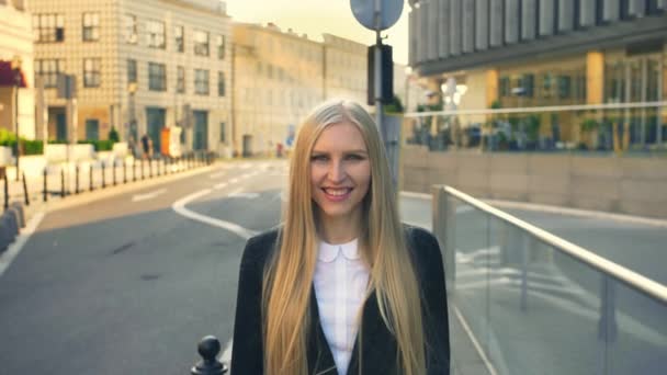 Femme d'affaires formelle marchant dans la rue. Élégante femme blonde en costume debout dans la rue avec le sourire sur fond urbain . — Video
