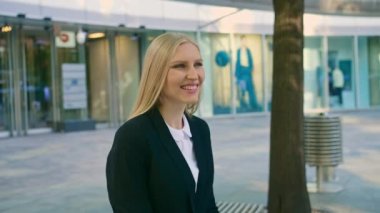 Neşeli çift kadın ile el sallayarak. Yetişkin sarışın iş kadını bankta oturan ve el tebrik meslektaşım Caddesi üzerinde sallayarak elbiseli.