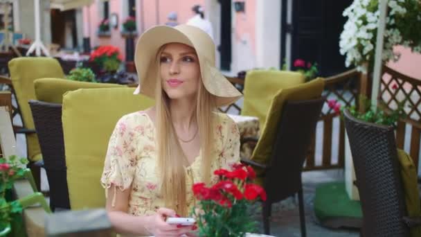 Smiling woman in outside restaurant. Cheerful young woman sitting at table in outside restaurant on cozy street. — Stock Video