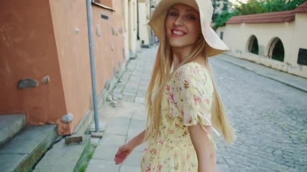 在城里散步时 戴着白帽 面带笑容的漂亮女人回头看相机 — 图库视频影像