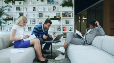 Ofiste büyük haber paylaşımı heyecan iş arkadaşları. Birlikte laptop ile kanepede oturan ve heyecanla büyük haber paylaşımı kadın ve çeşitli erkeklerin yan görünüm.