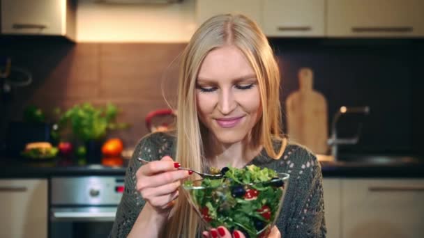 Frohe Frau, die gesunden Salat isst. schöne junge Frau genießt gesunden Gemüsesalat, während sie in stilvoller Küche sitzt. — Stockvideo