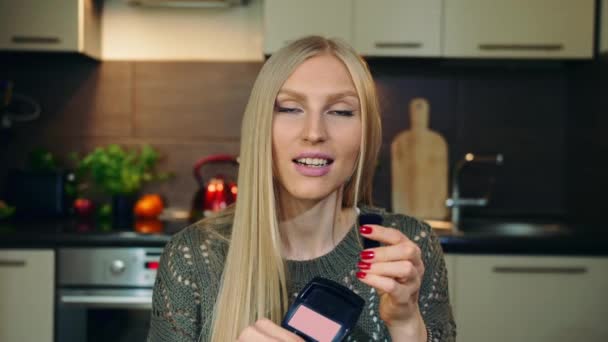 Junge Vlogger sprechen über Make-up erröten für Gesicht. Attraktive junge Frau spricht über kosmetische Rouge für das Gesicht, während Videoaufnahmen für Schönheit vlog in der Küche. — Stockvideo