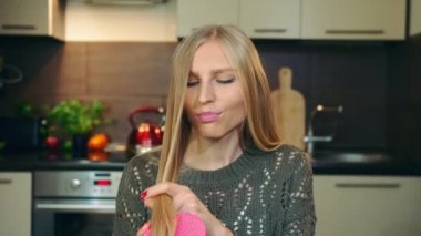 Genç vlogger kamera için saç tarıyor. Güzel genç bir kadın, güzel bir mutfakta güzellik bloğu için video çekerken saçlarını tarıyor..